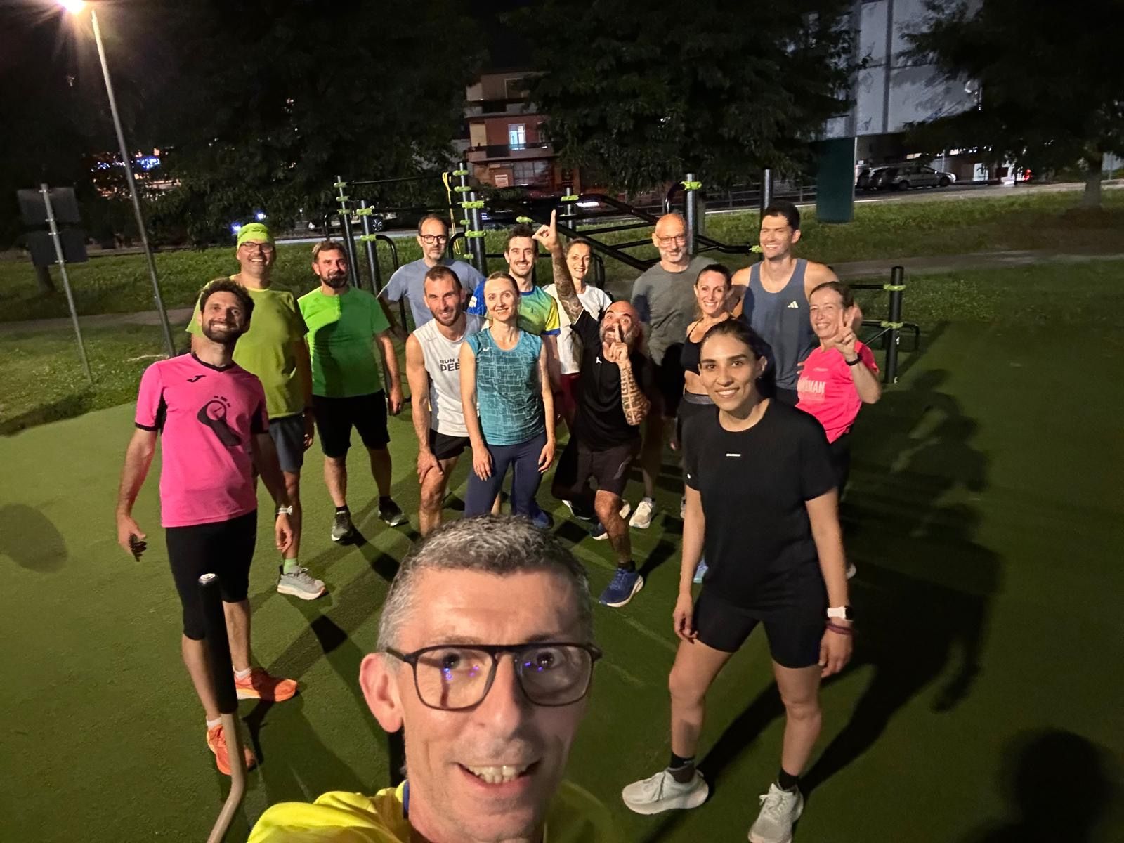 Selfie di gruppo del team Let's Run durante un allenamento serale al parco calisthenics