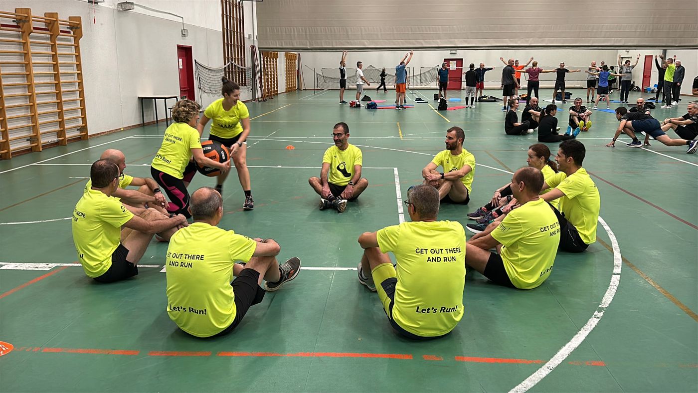 Gruppo Let's Run seduto in cerchio durante il riscaldamento guidato in palestra a Treviglio